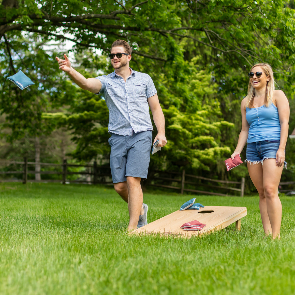 To venner spiller cornhole sammen i en grøn have