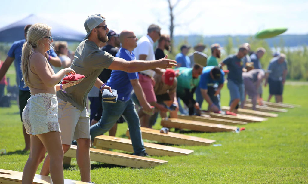 Cornhole-spillere ved en udendørs turnering på græsset